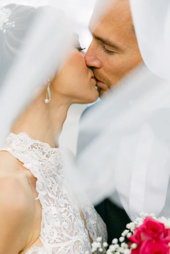 Gros plan des mariés s’embrassant sous le voile, photo de mariage fine art